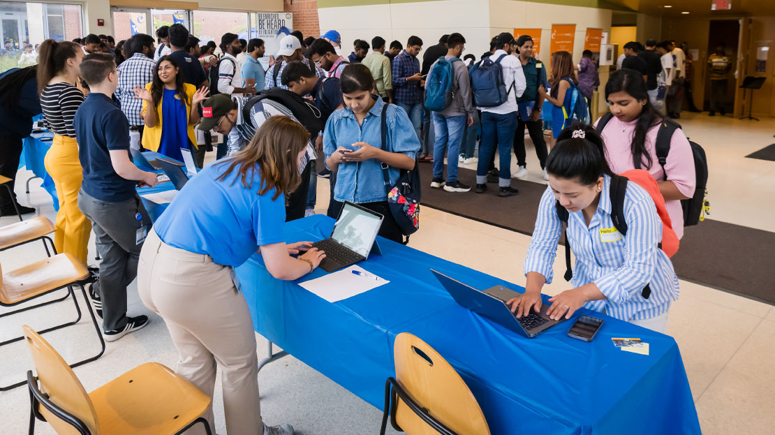 Students check in at a booth during Webster's international graduate orientation.